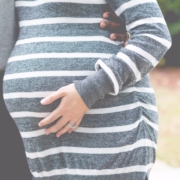 mid-section-of-pregnant-woman-with-mans-arm-around-her