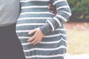 mid-section-of-pregnant-woman-with-mans-arm-around-her