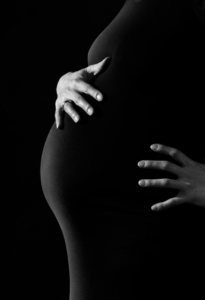 midsection-of-pregnant-woman-in-black-dress-with-hands-on-her-belly