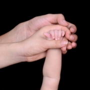 two adult hands holding a baby's hand