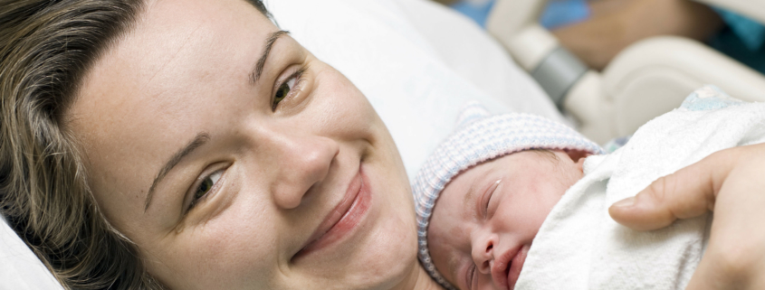 Smiling woman holding newborn baby